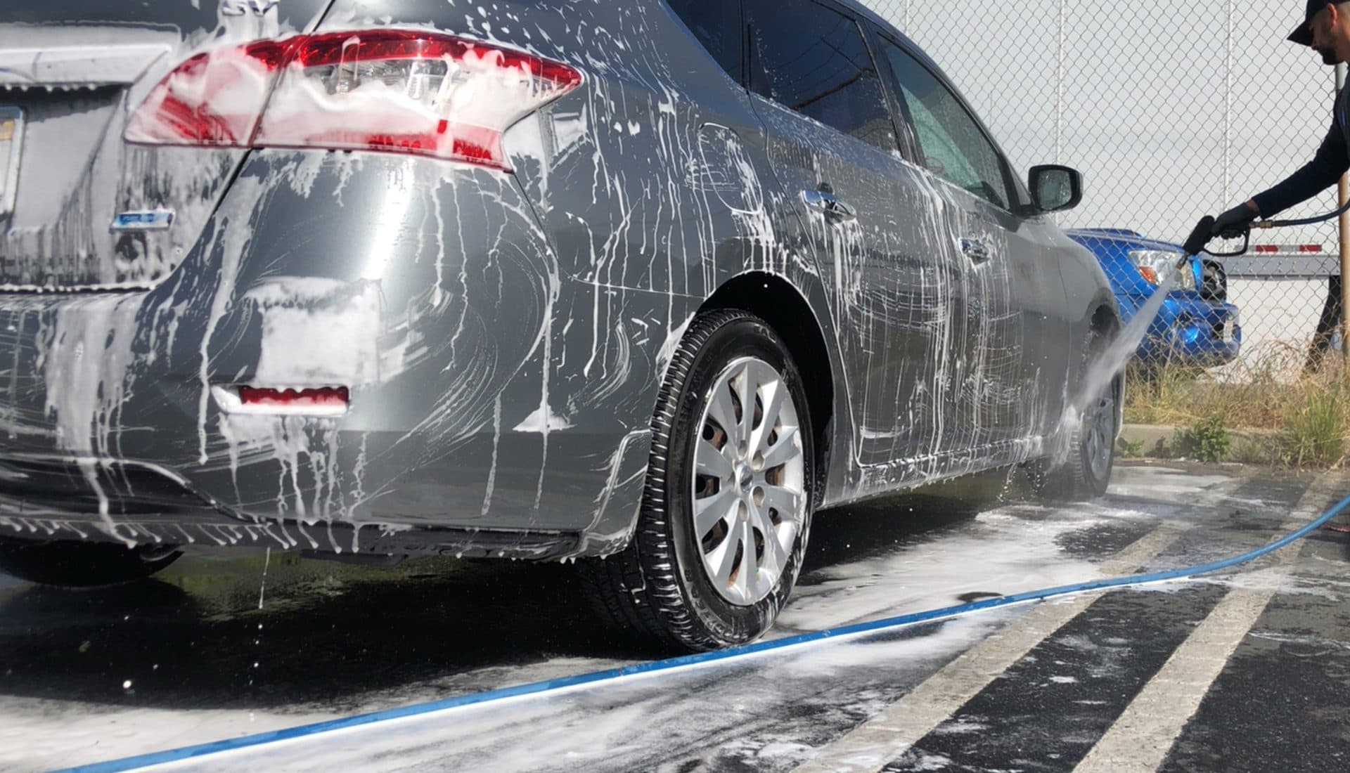 Grey sedan covered in foam during a hand wash