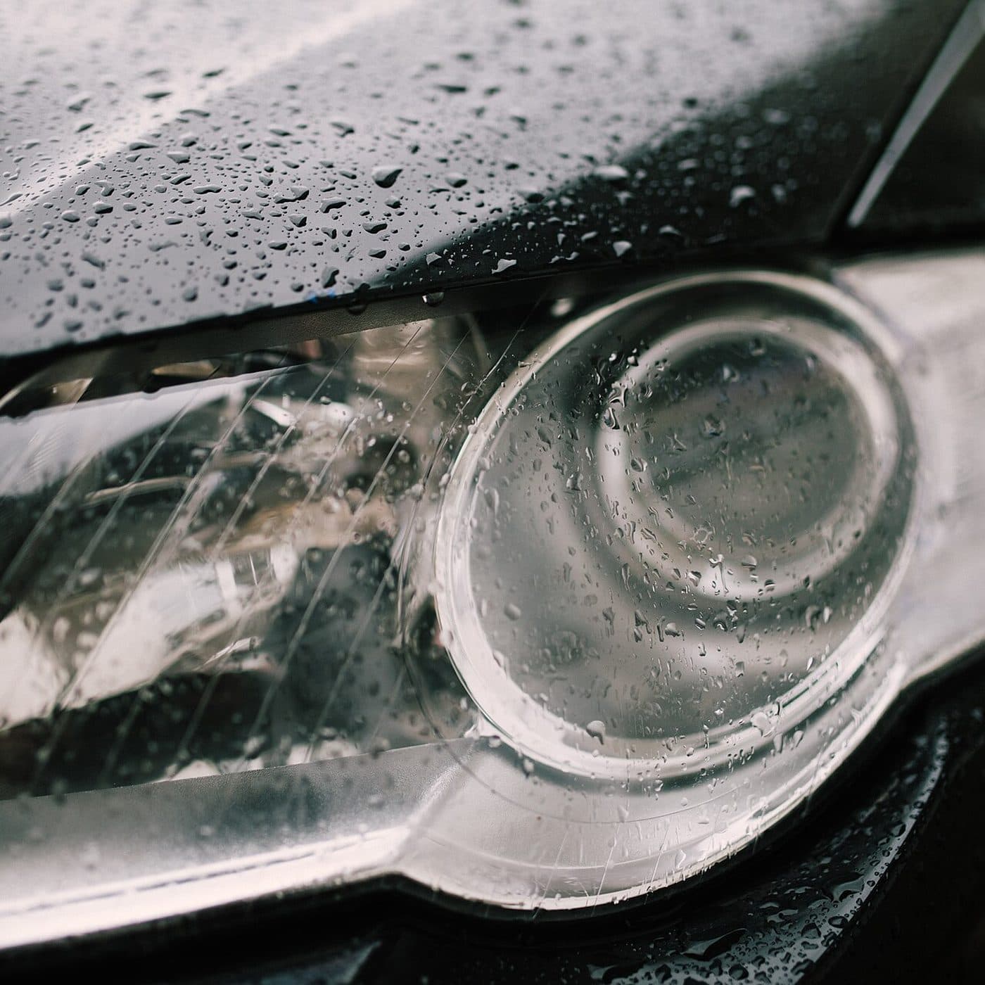 Water beading on a dark car's headlight and fender