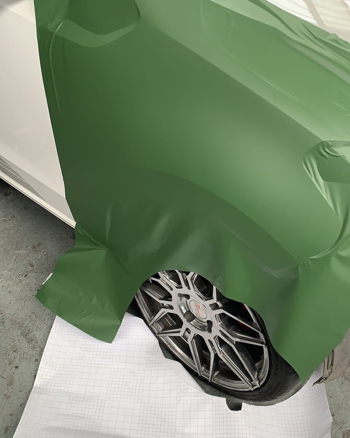 Installer working vinyl film around a wheel arch