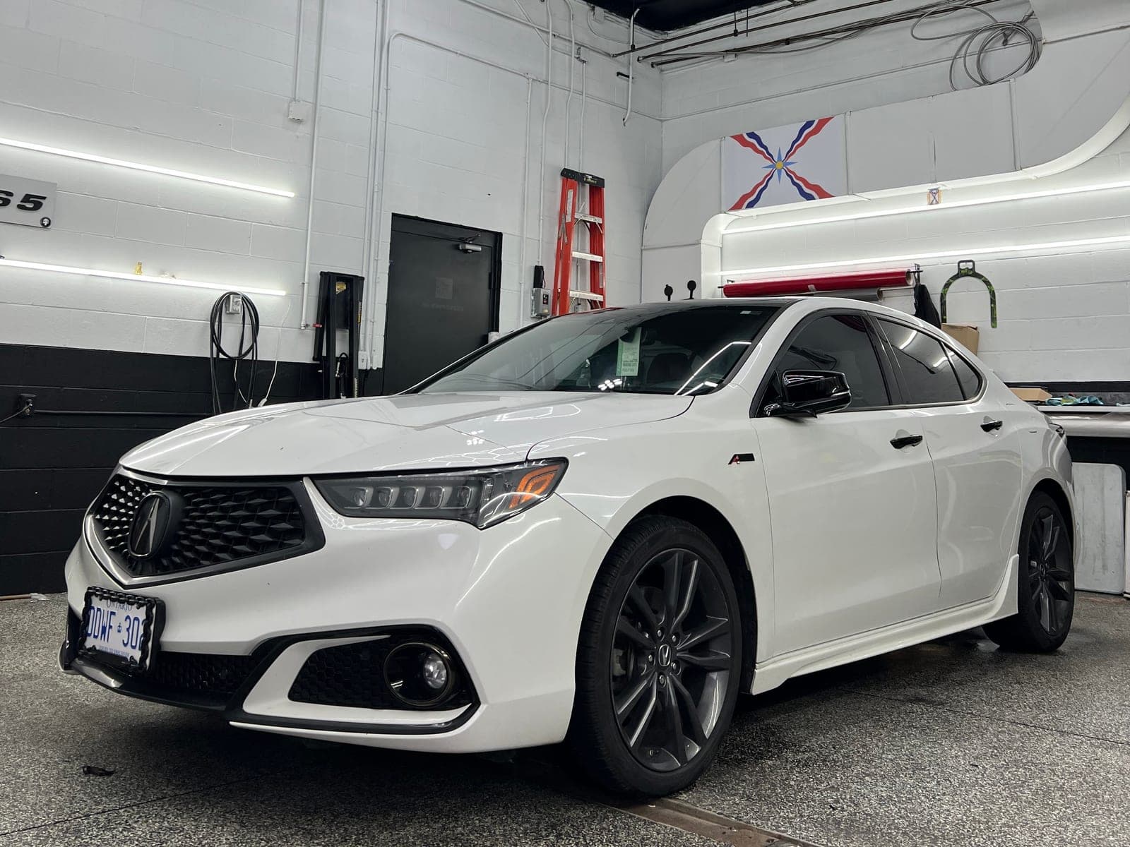 Pearl white Acura TLX A-Spec with dark wheels freshly detailed inside the WrapLab shop