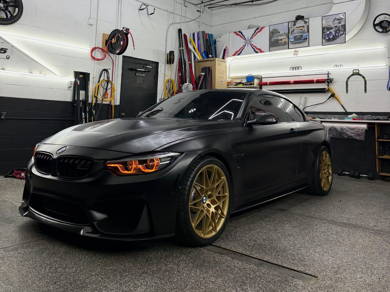 BMW M4 in 3M satin black with gold wheels and orange headlight accents