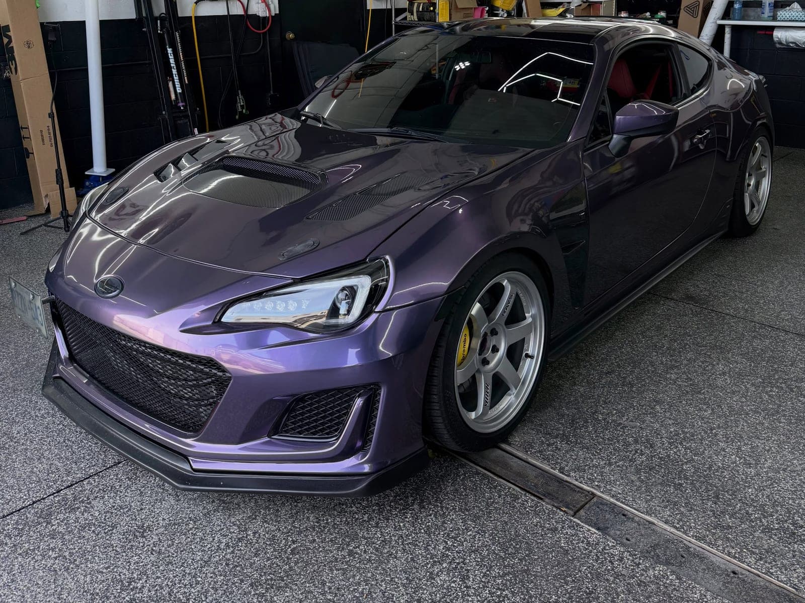 Violet Subaru BRZ with the hood and fenders wrapped to expose carbon