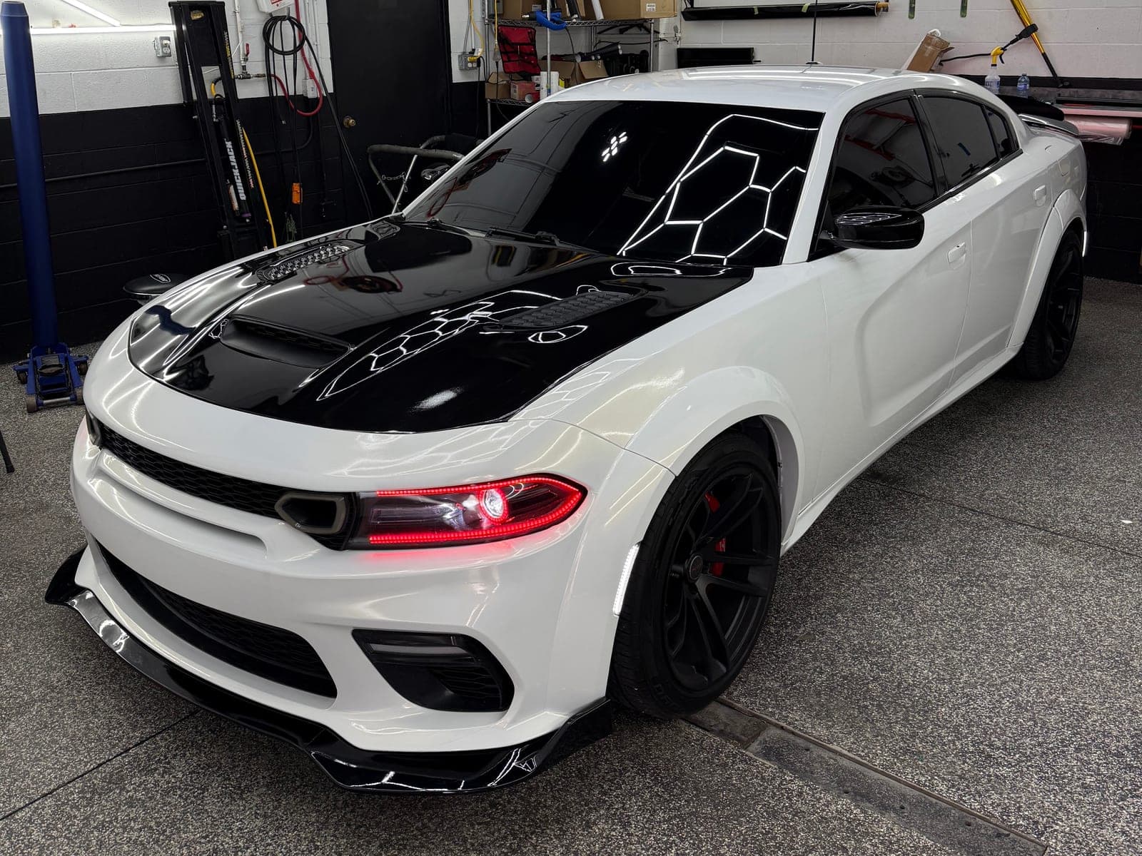 White Dodge Charger Widebody with a gloss black wrapped hood and red headlight accents