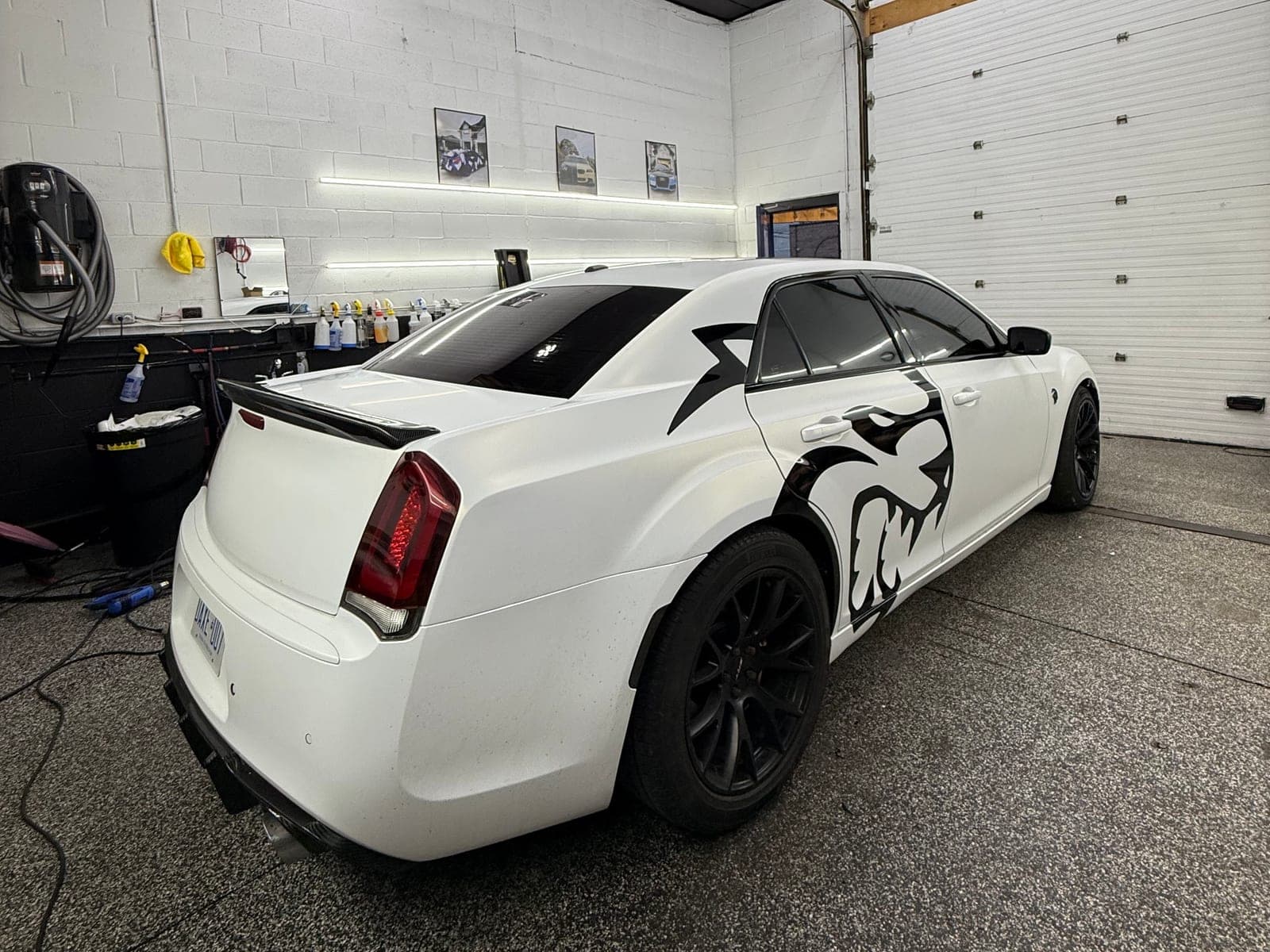 White Chrysler 300 with a large black cut-vinyl Hellcat graphic across the rear quarter