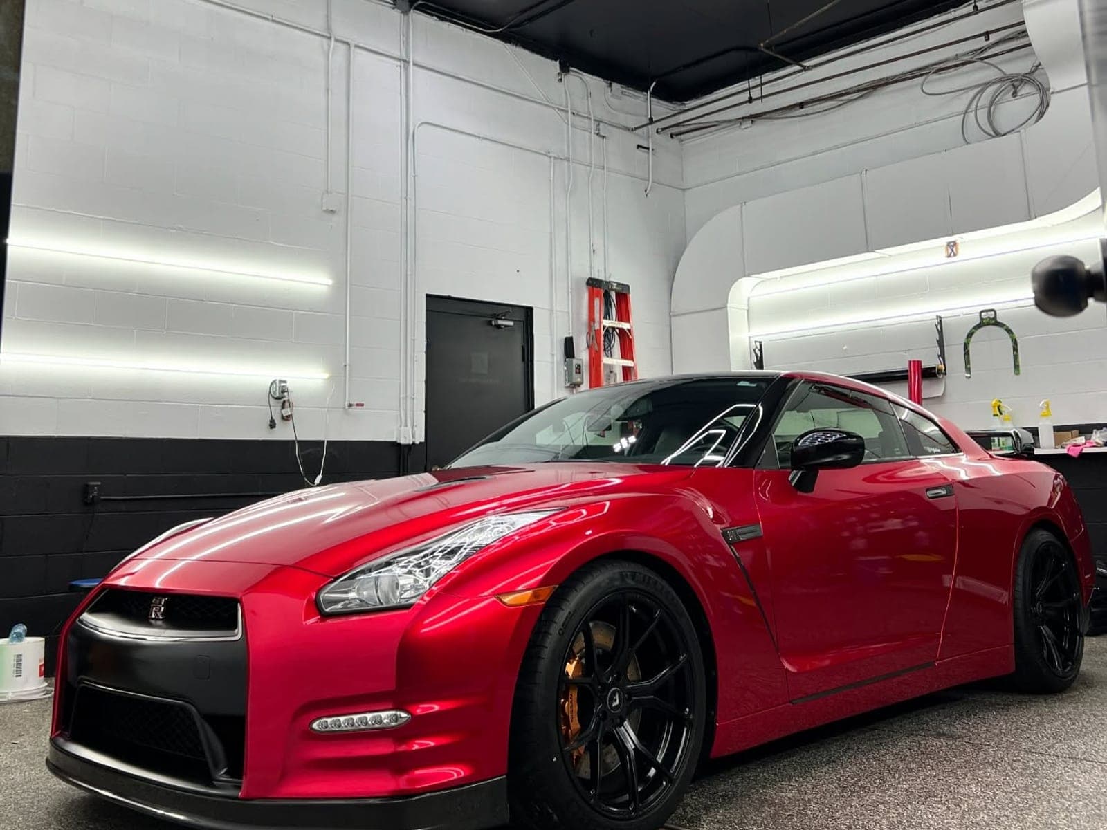 Nissan GT-R in gloss vampire red with black wheels inside the shop