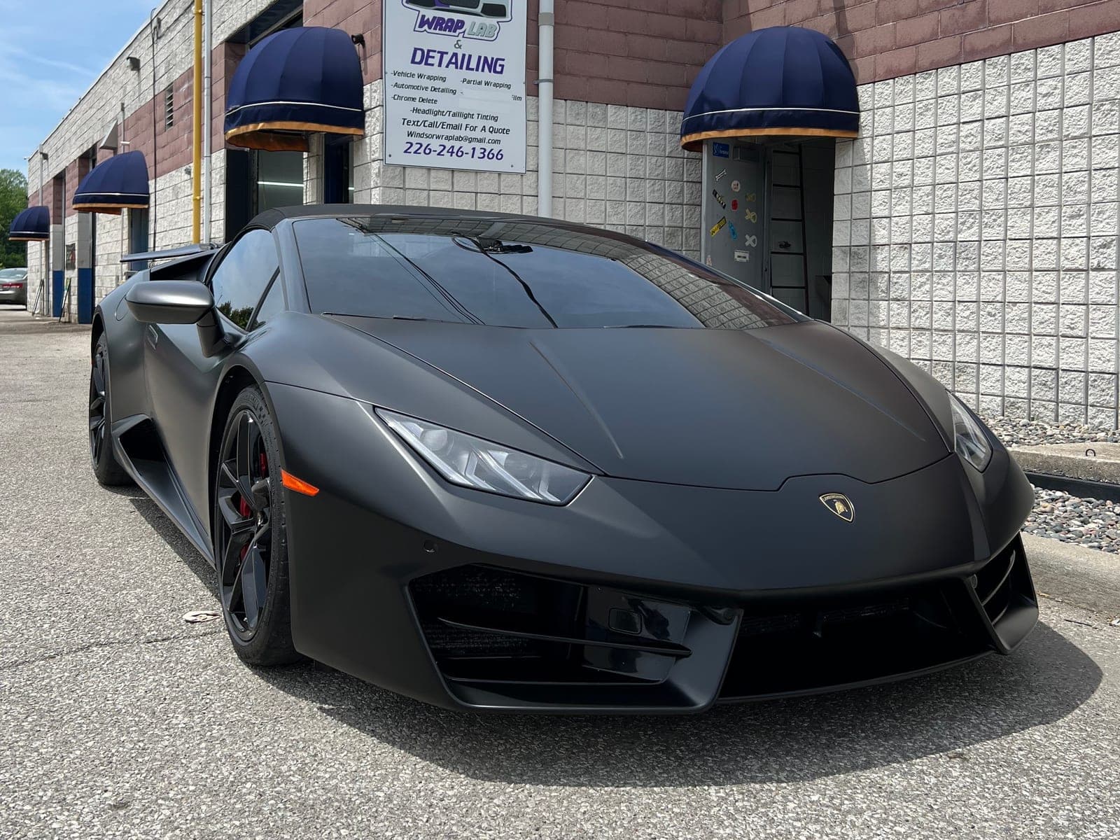 Satin black Lamborghini Huracán Spyder parked in front of the WrapLab shop on Lauzon Road
