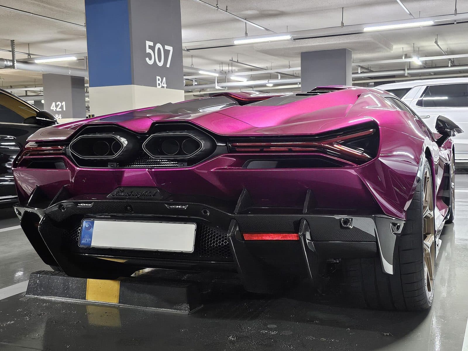 Rear of a metallic violet Lamborghini in a garage