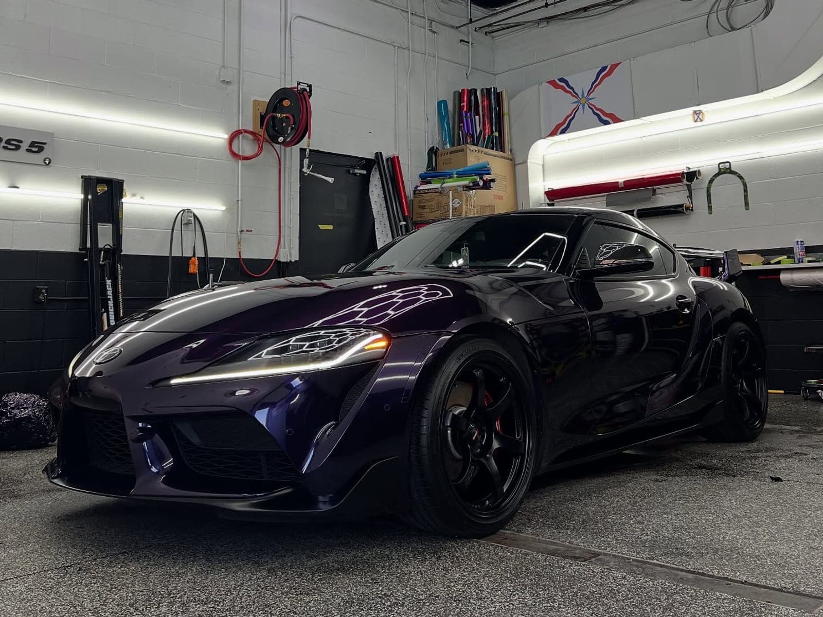 Toyota GR Supra wrapped in a dark black-violet colour shift under hexagon lights