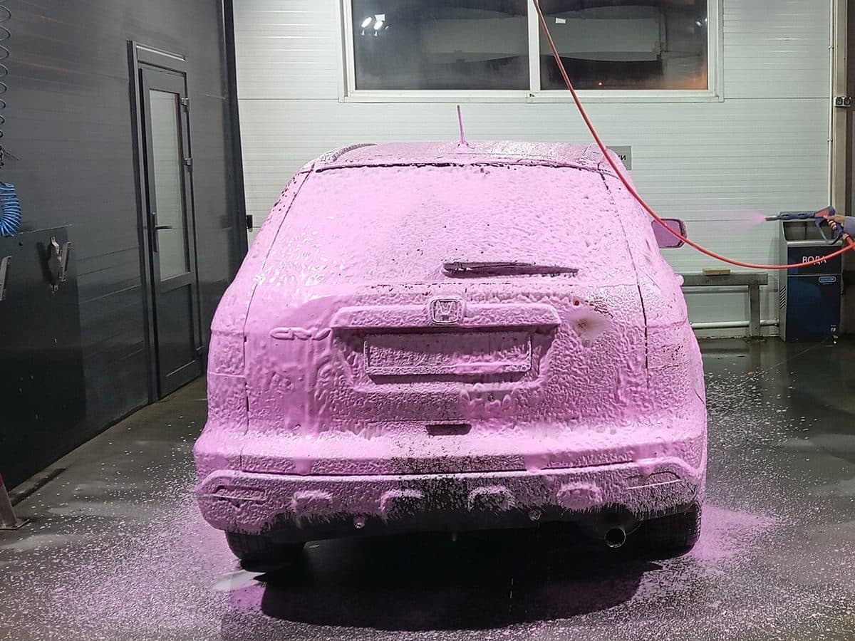 SUV covered in pink foam in a wash bay